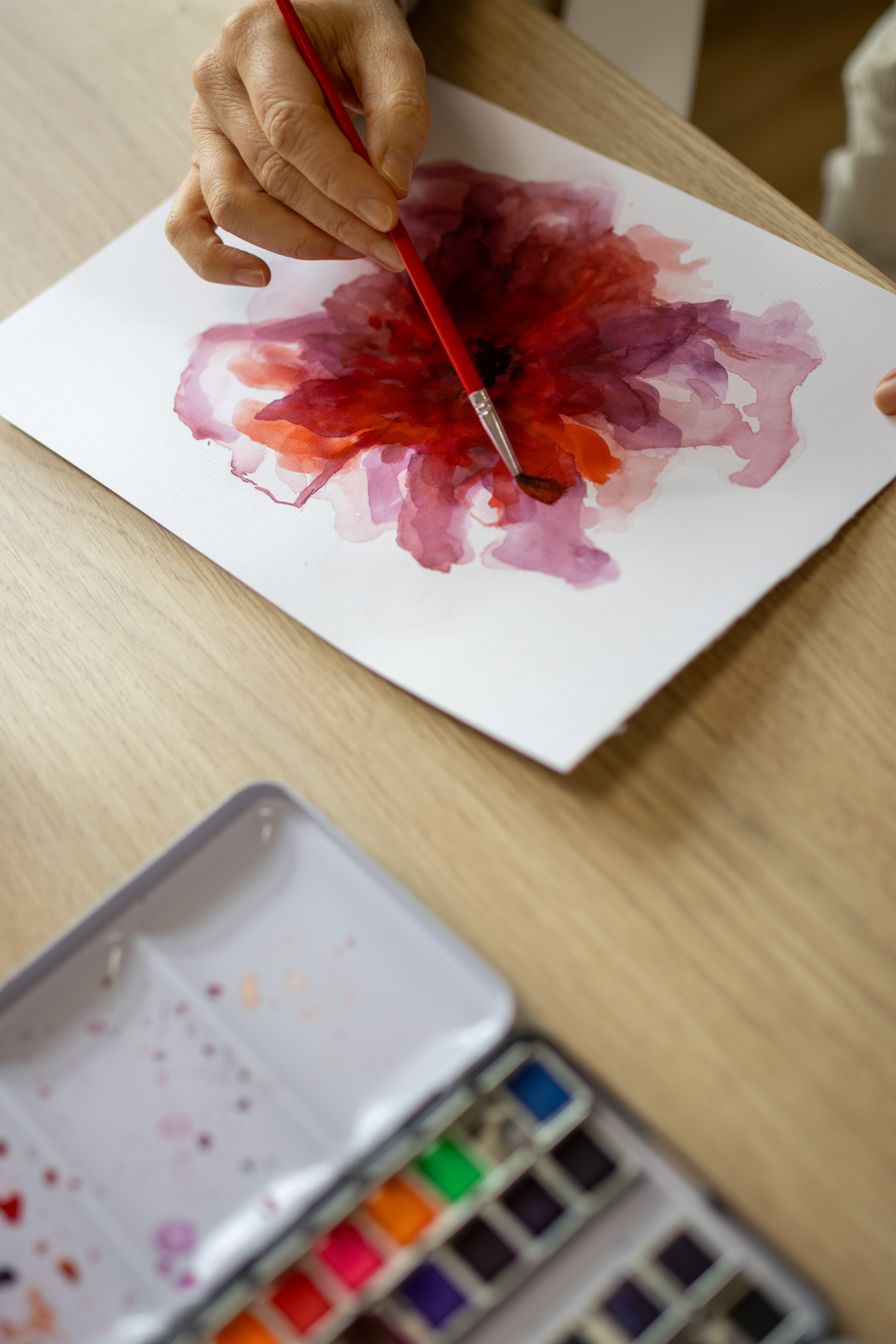 En hånd maler en blomst med vandfarve