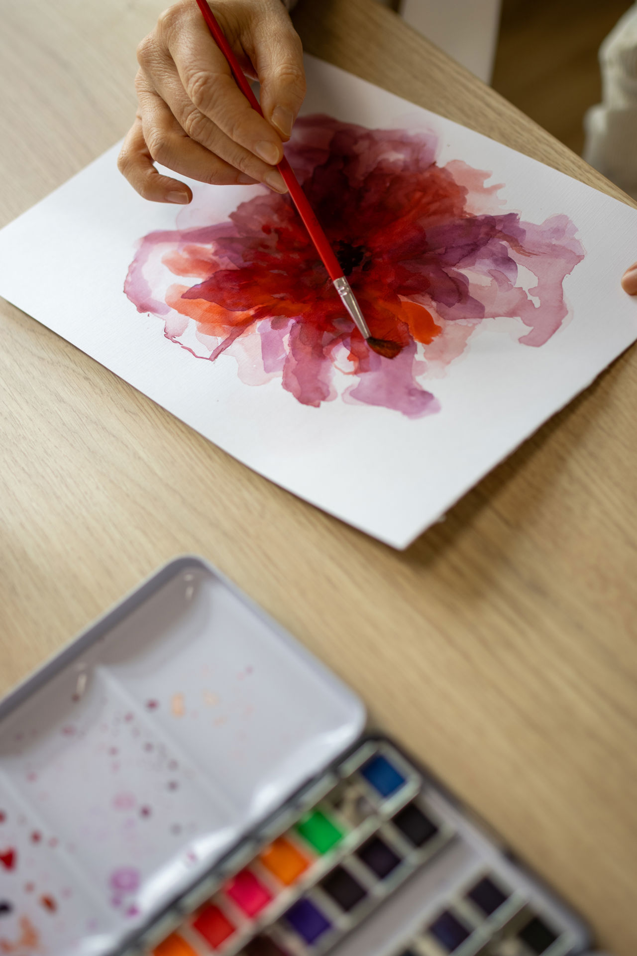 En hånd maler en blomst med vandfarve